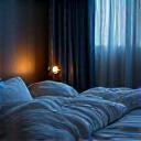 Person sleeping peacefully in a comfortable, dark bedroom, with soft light from a window.